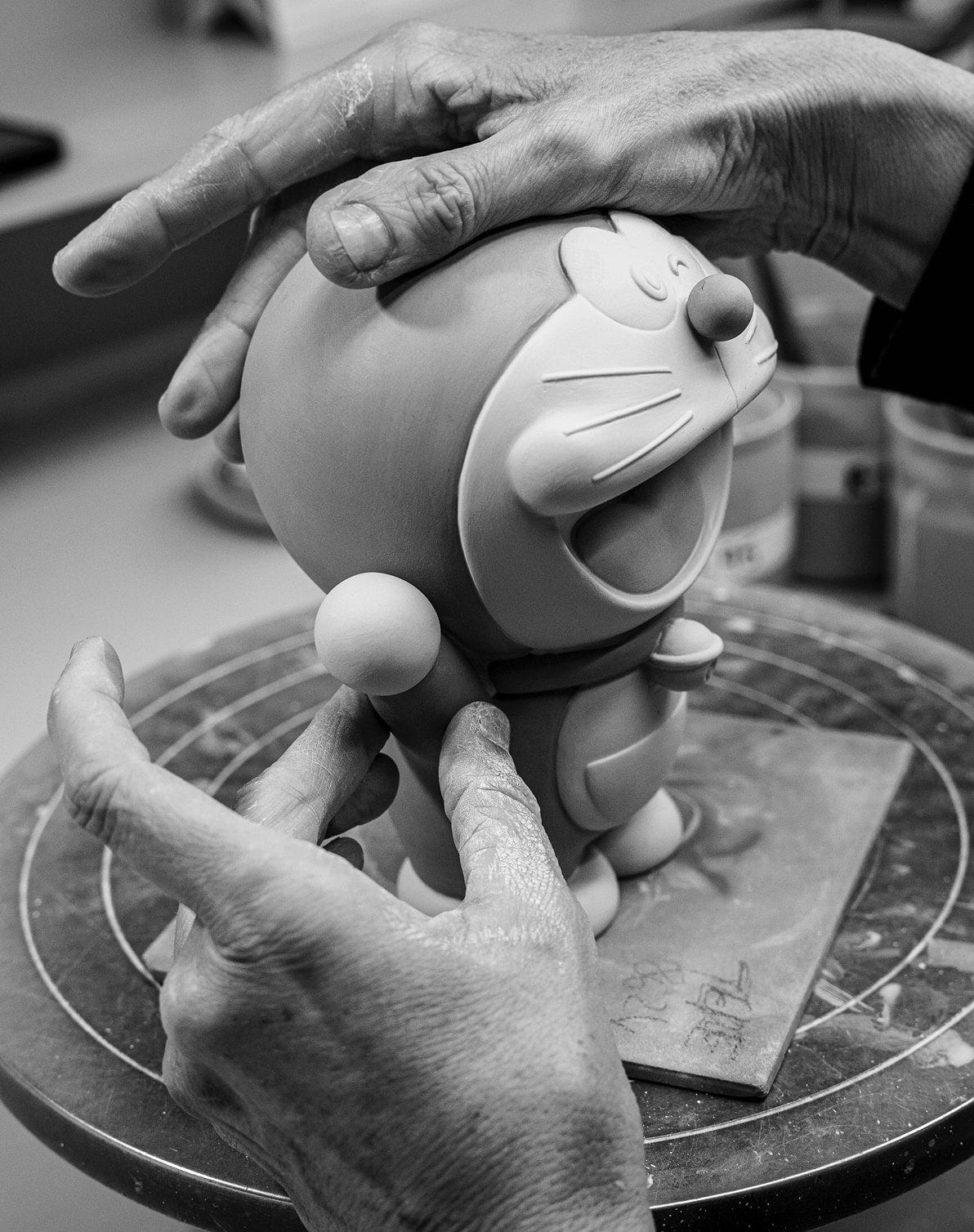 Artigiano che dipinge a mano i dettagli di una figura di Doraemon