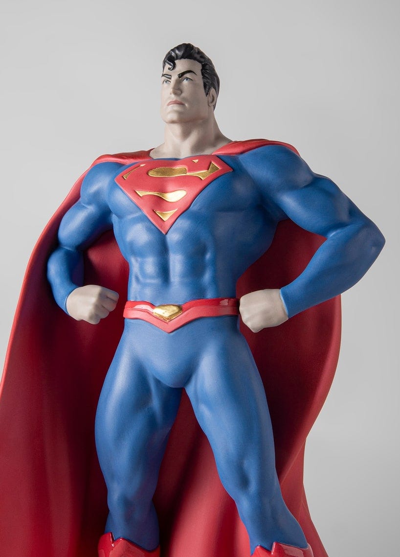 Figura de Superman en porcelana hecha por Lladró, erguida con las manos en la cintura. Lleva un traje azul, una capa roja ondeante y el emblemático emblema rojo y amarillo en el pecho.