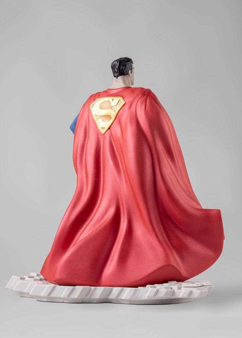 Vista trasera de la figura de Superman de Lladró, destacando los volúmenes esculpidos y el movimiento fluido de la capa roja mate.