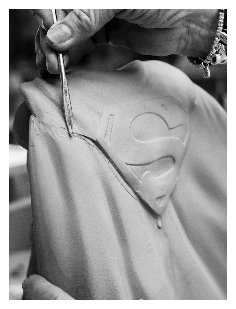 Detalles del trabajo artesanal en la figura de Superman en porcelana sin pintar, refinando los rasgos faciales a mano.